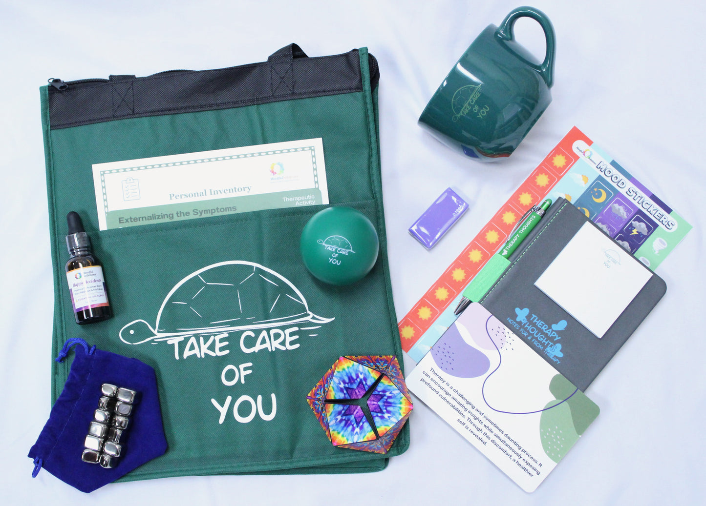 a fabric bag with handles, mood stickers, therapy journal, mug, essential oil, stress ball, figit, notepad, pen