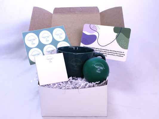 medium white box with a mug, postcard, notepad, stress ball, stickers